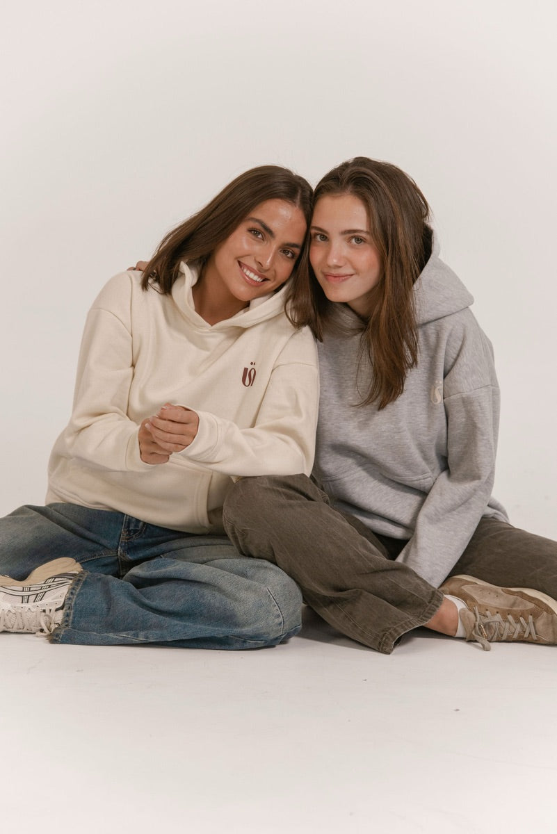 Dos amigas sentadas con hoodies crema y gris de Once Once