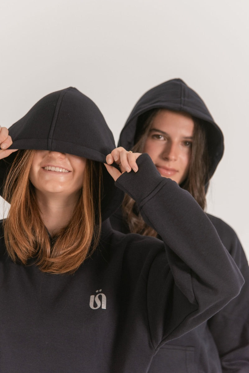 Dos amigas con la capucha puesta y hoodies negro y azul marino